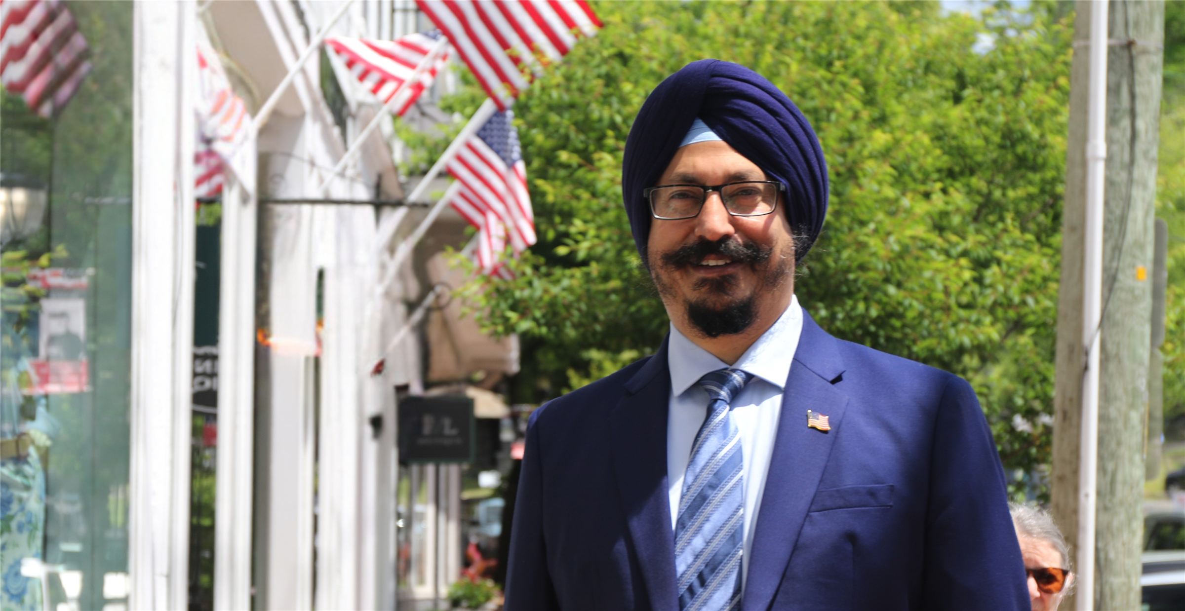 Harjot Singh smiling on a Huntington street lined with American flags